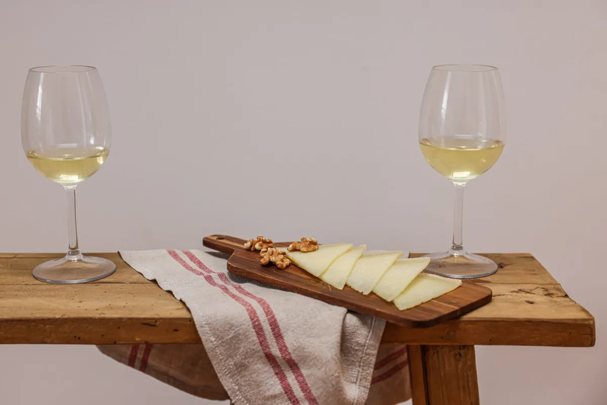 Taça de vinho ao lado de uma tábua de queijos